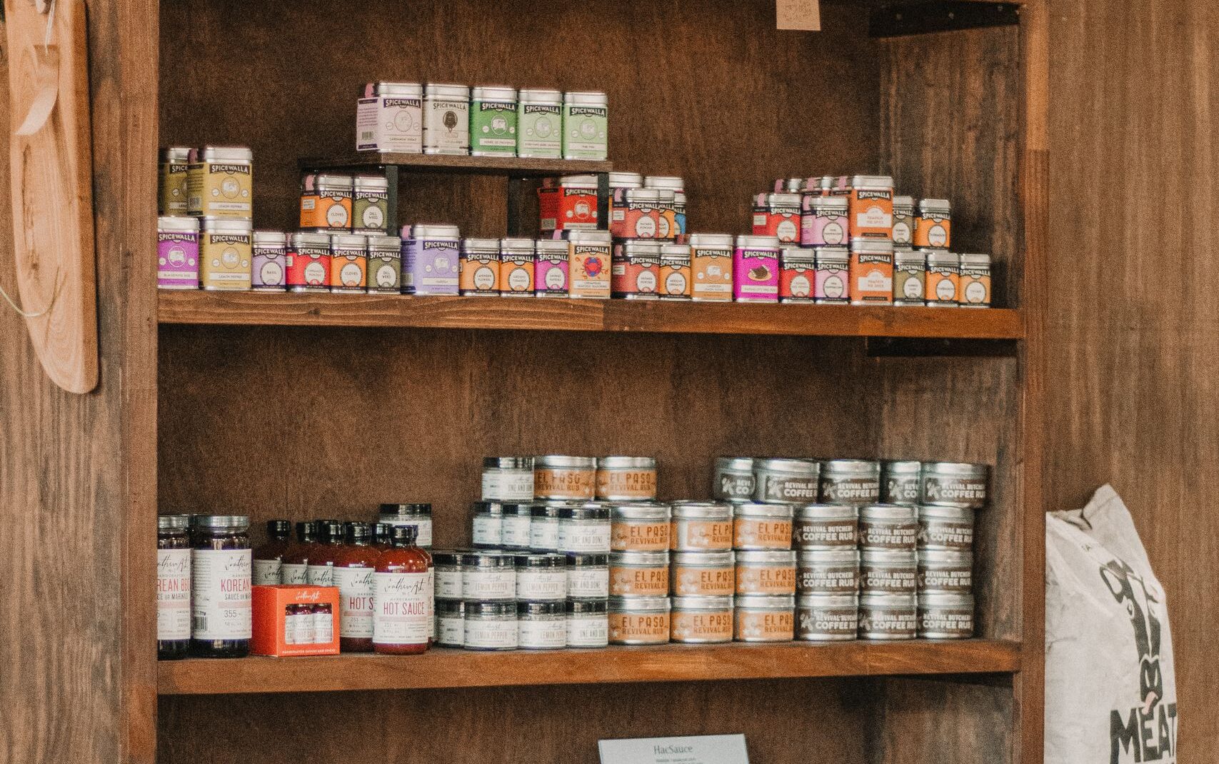 A rustic wooden shelf displaying local meat and condiments at a South Carolina butcher shop.