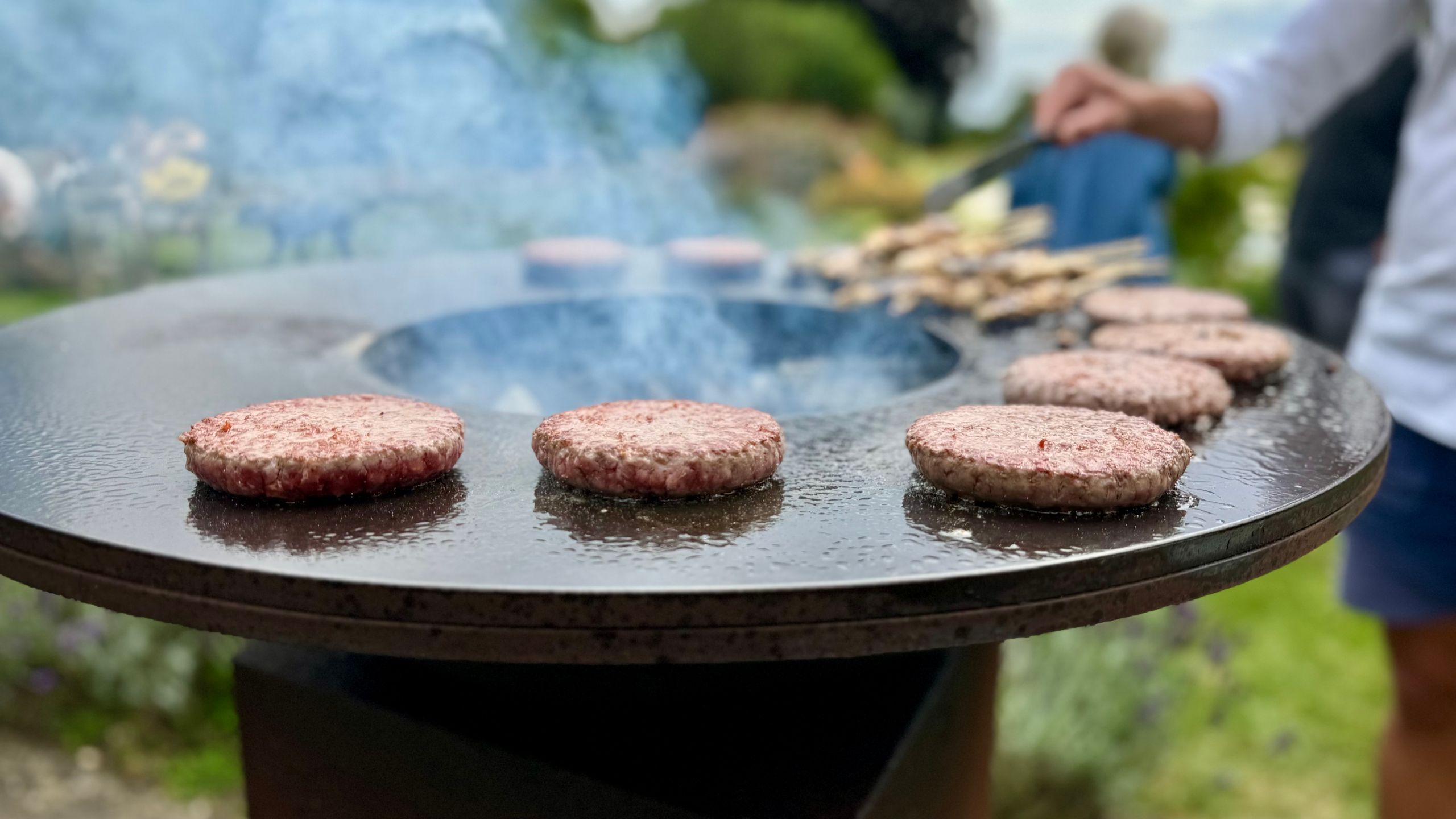 Delicious beef patties grilling on a plancha during an outdoor barbecue in Henley-on-Thames.