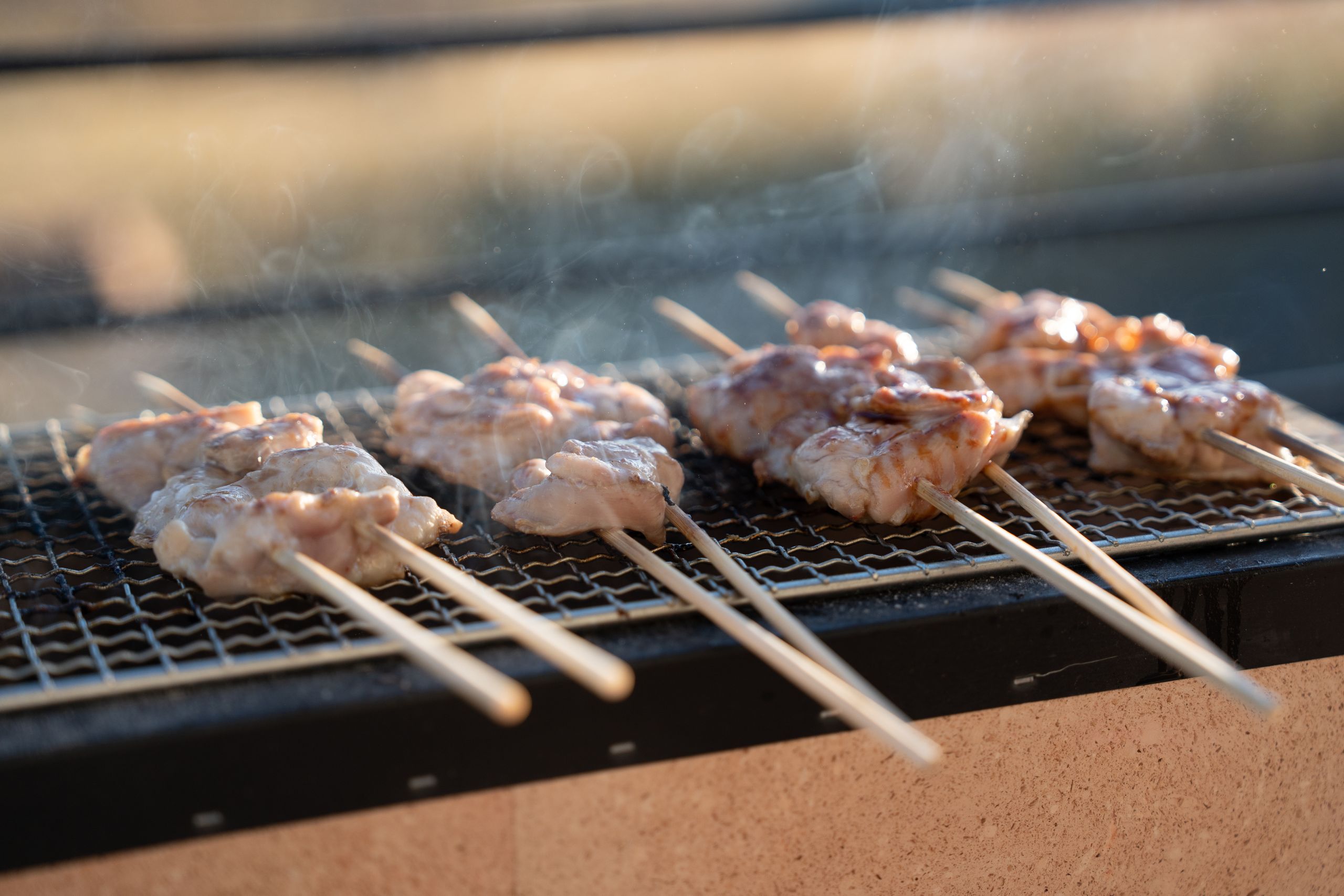 Juicy meat skewers roasting on a grill, outdoors with a touch of smoke.