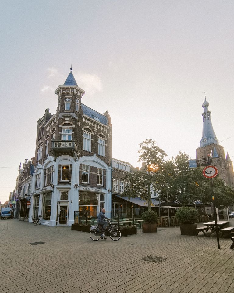 A cyclist rides through a picturesque old town with historic architecture at sunset.