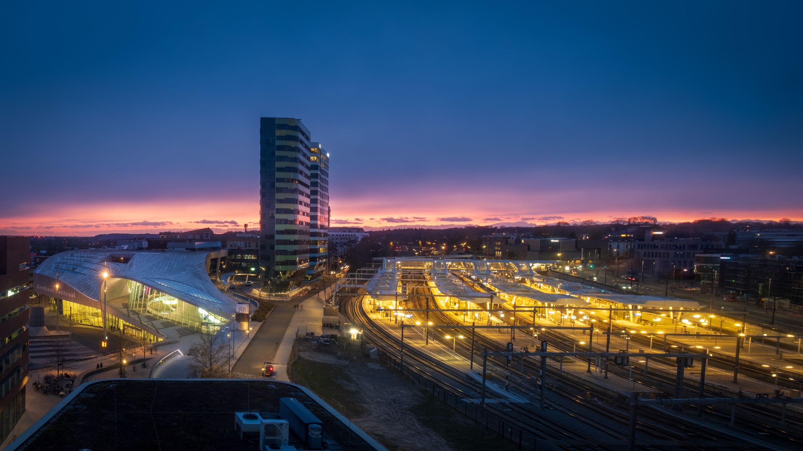 Explore the illuminated Arnhem Central Station at sunset, showcasing urban architecture in the Netherlands.