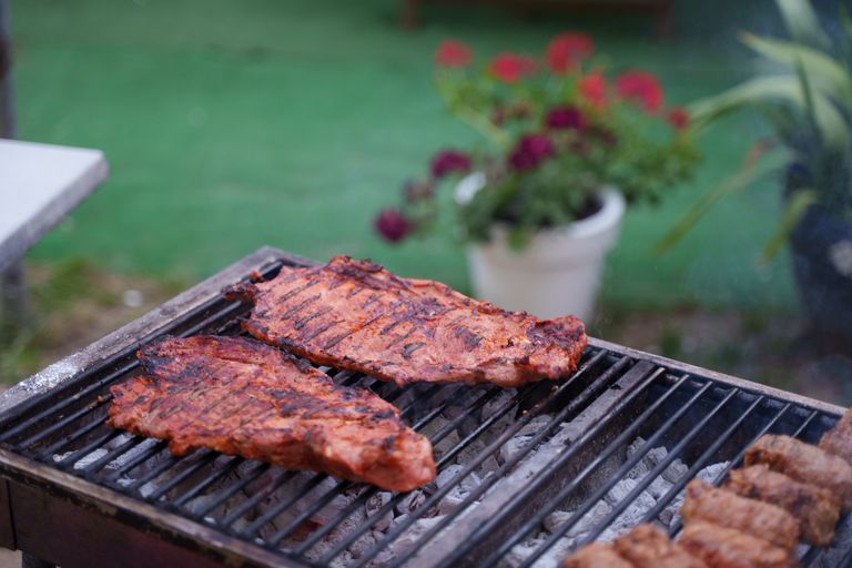 Juicy ribs sizzling on a charcoal grill in a garden setting. Perfect for summer BBQs.