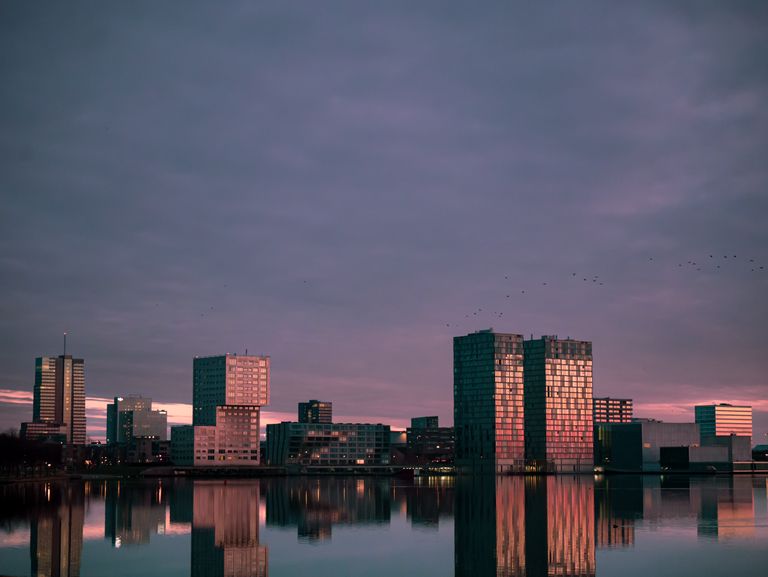 Modern skyline of Almere, Netherlands, reflecting on calm water at dusk.